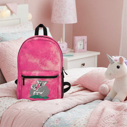 Pink backpack with a koala design on a pink and white bed