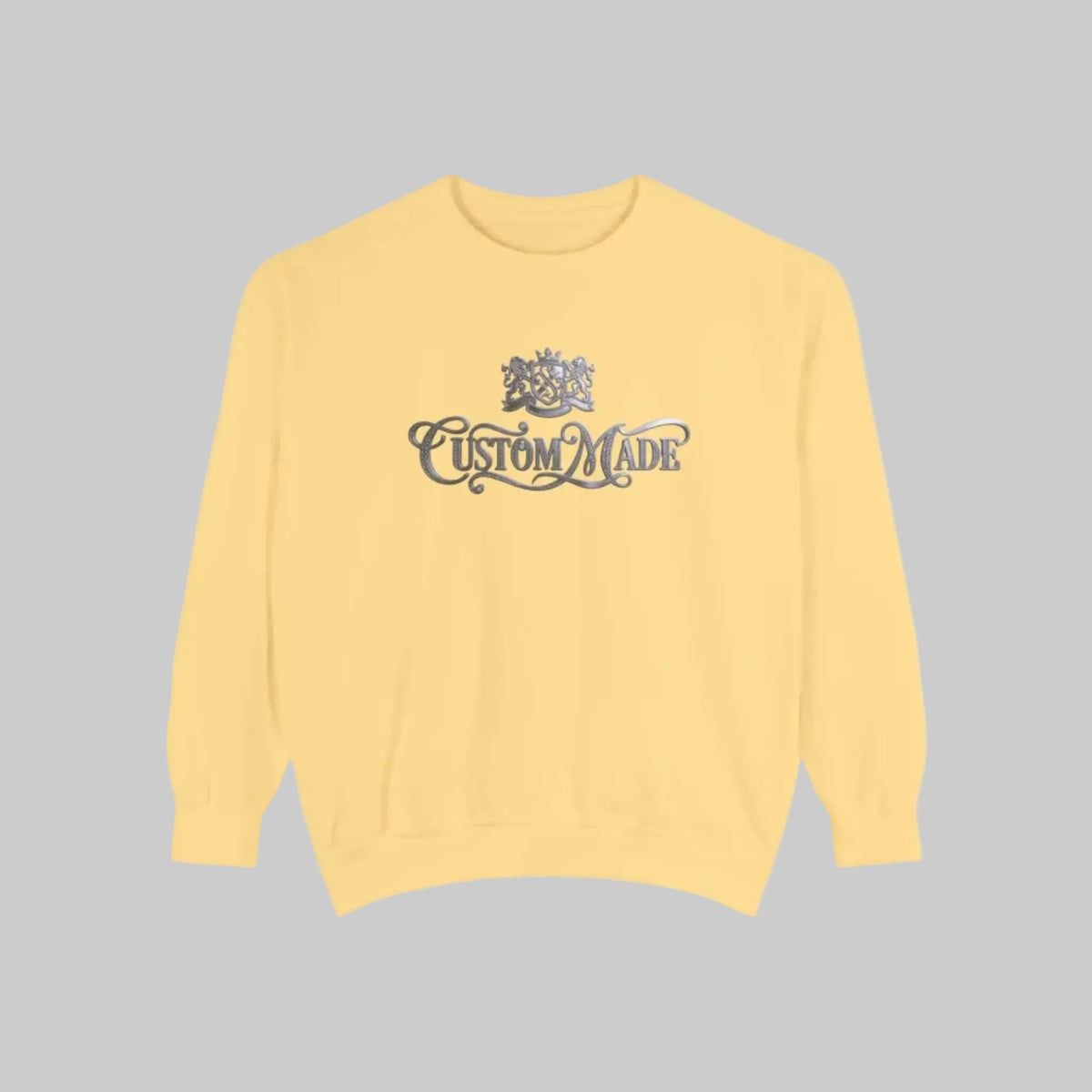 Butter yellow crewneck sweatshirt with a silver graphic on the chest featuring a crest and the words 'CUSTOM MADE'.