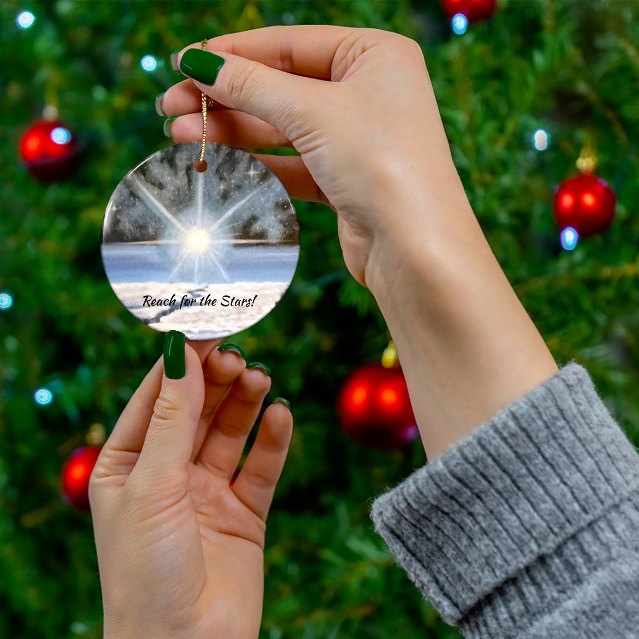 Hand holding a reflective ornament with 'Reach for the Stars!' text