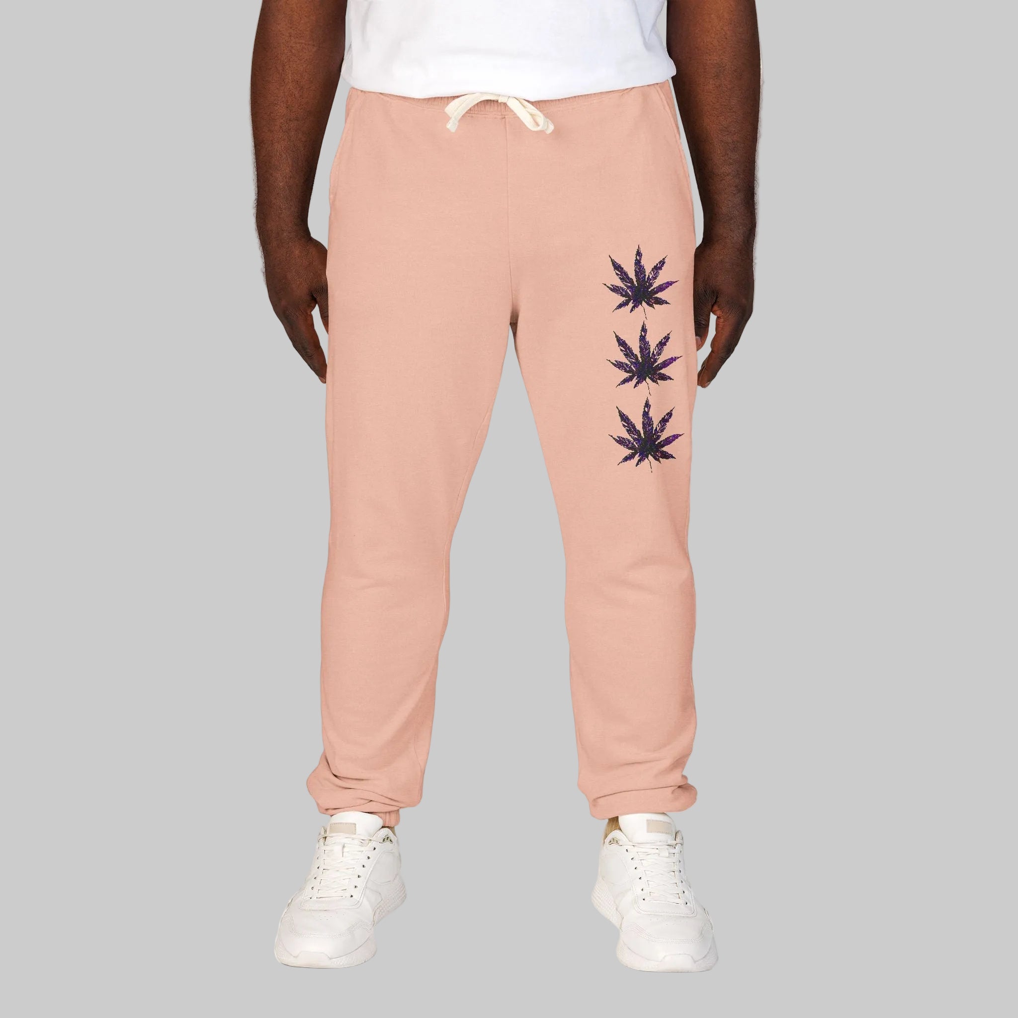Unisex peachy-colored sweatpants with a vertical graphic of three cannabis leaves on the left leg stating your vibe and chi