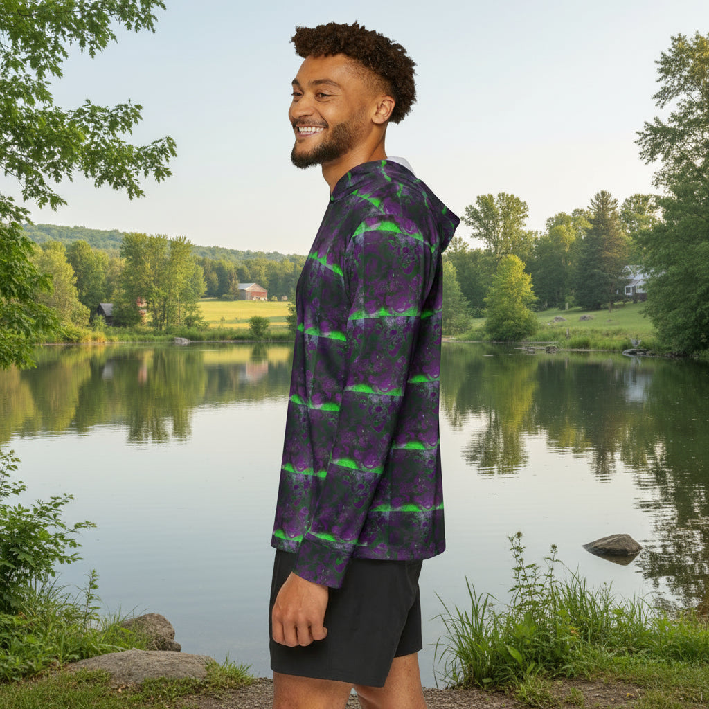 Man wearing a purple and green patterned hoodie standing by a lake background