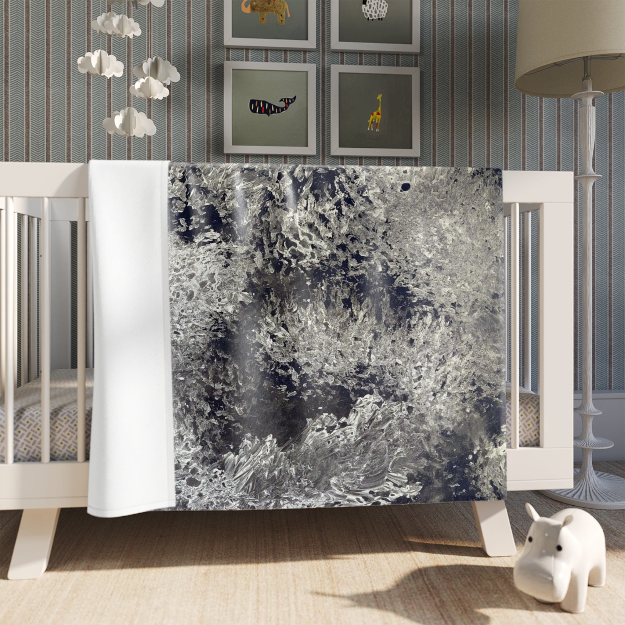 Abstract patterned blanket draped over a crib in a nursery setting.