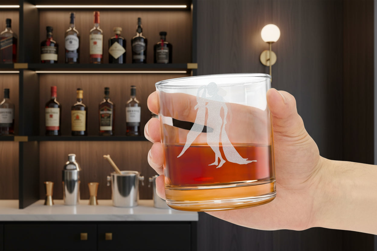 Hand holding a heavy bottom whiskey glass with a Naked Art Deco Divas