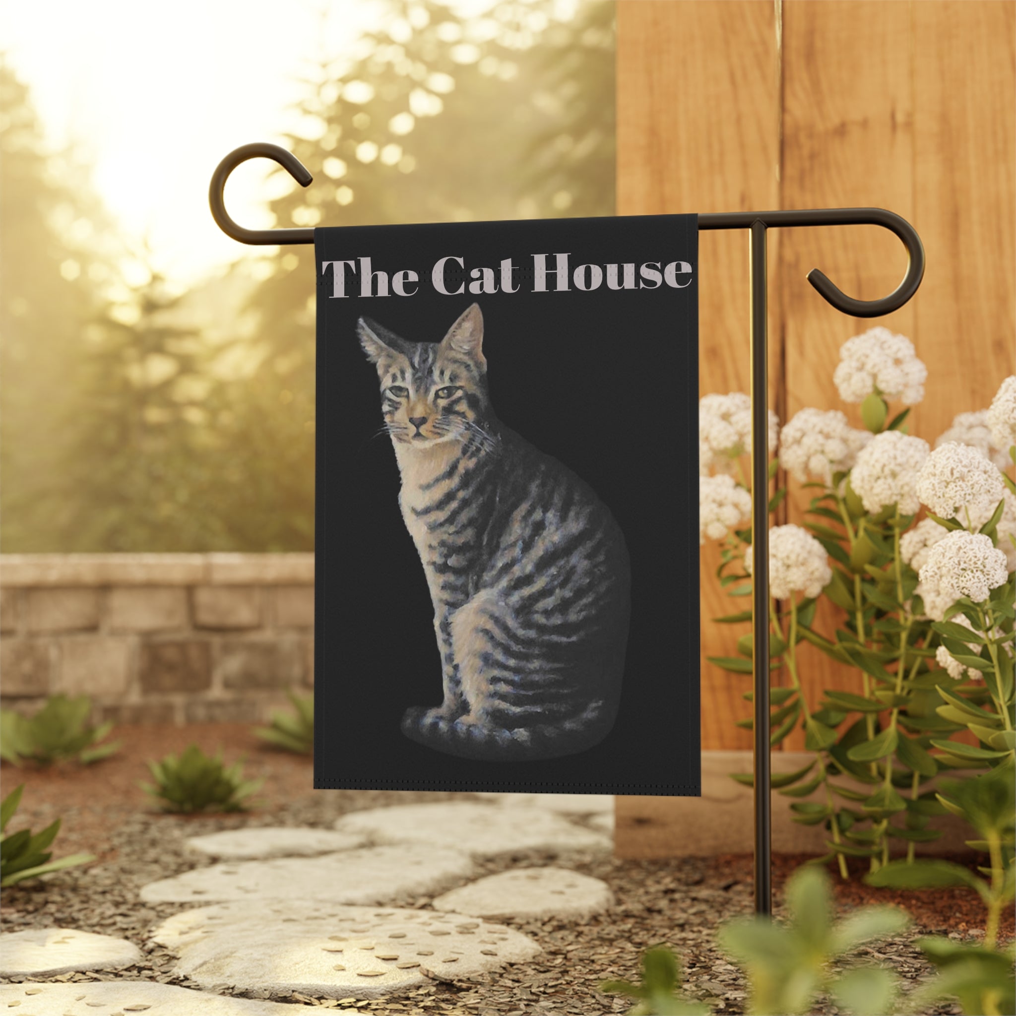Garden flag with a cat design and 'The Cat House' text, displayed outdoors.