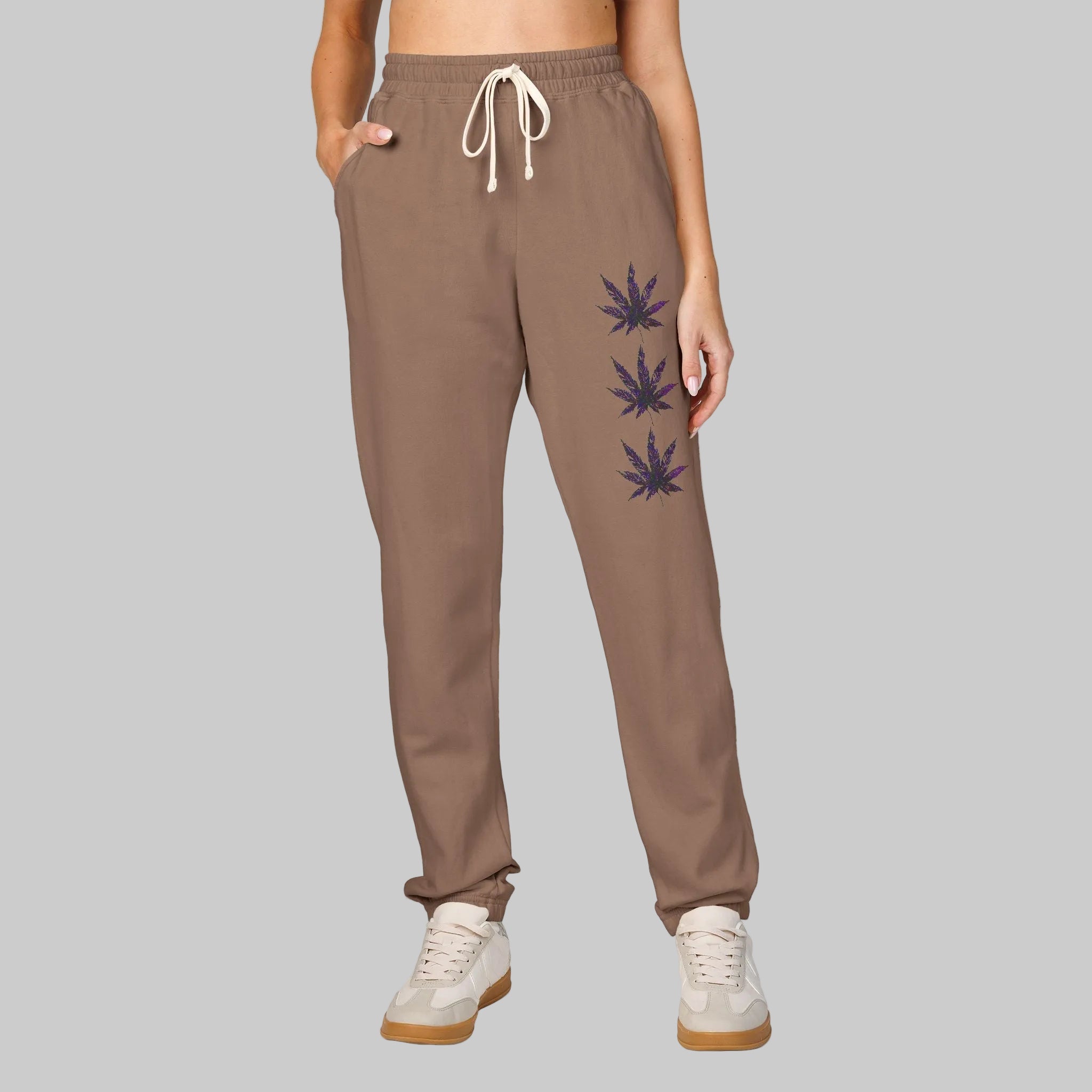 Women's or Men's jogger/lounging sweatpants with a white drawstring and three dark cannabis leaf graphics printed vertically on the left leg reveals your relaxed vibe.