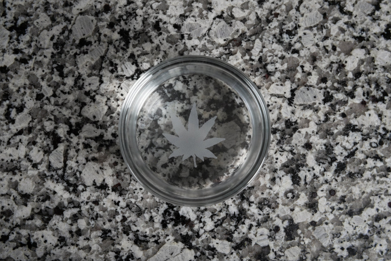 Clear Whiskey Glass heavy bottom is engraved with a Cannabis Leaf