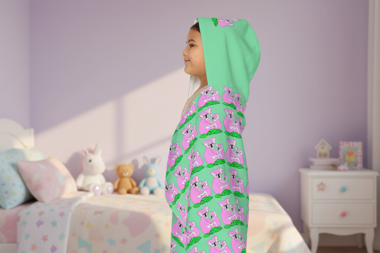 child wearing a green and pink patterned hooded towel in her bedroom