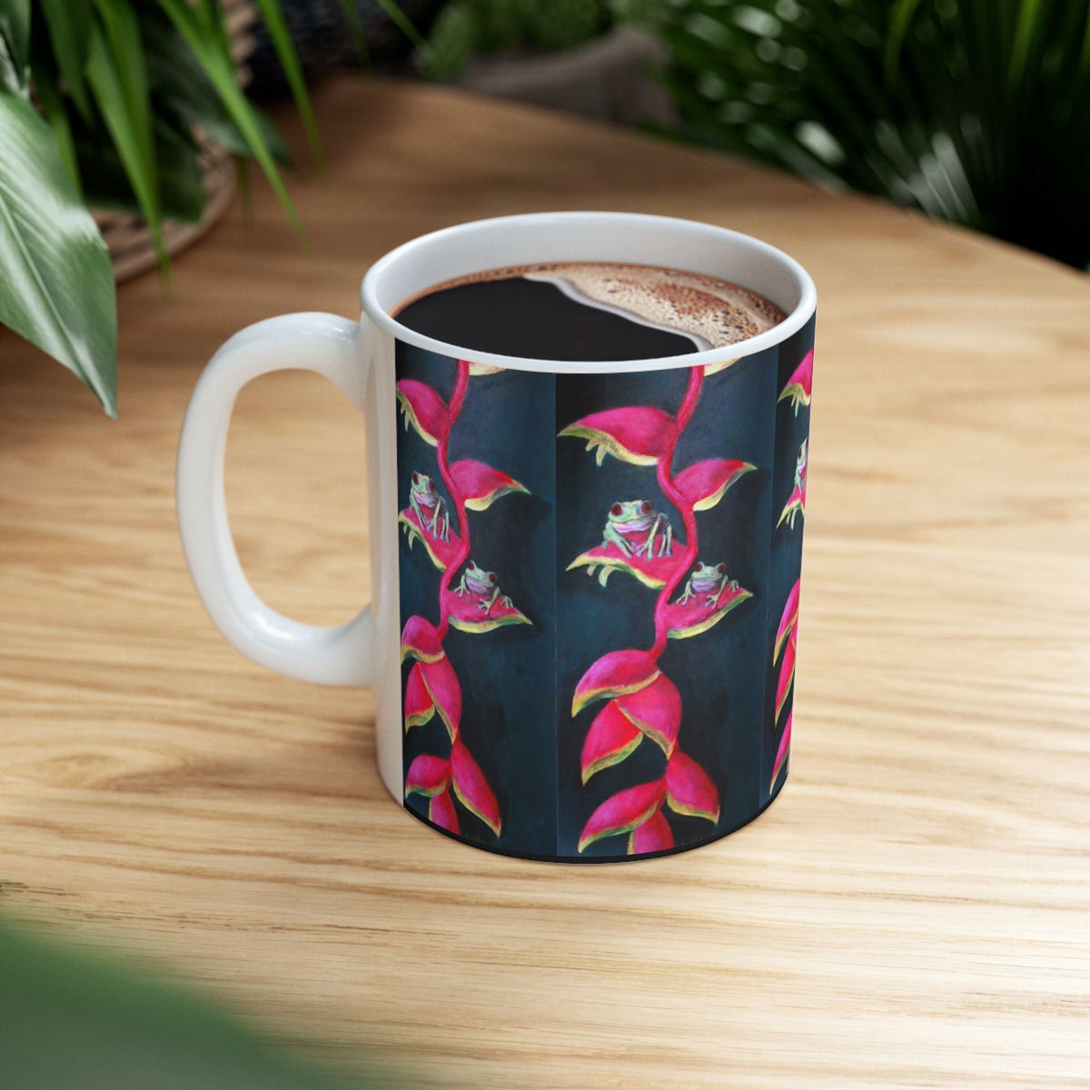 11oz white ceramic coffee mug  featuring a wrap-around pattern of bright pink and magenta tropical flowers and little green frogs on a dark background.