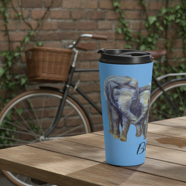 A light blue travel tumbler with a black leak proof lid, featuring a printed illustration of two elephants on either side