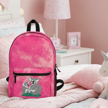 Pink backpack with a koala design on a pink and white bed
