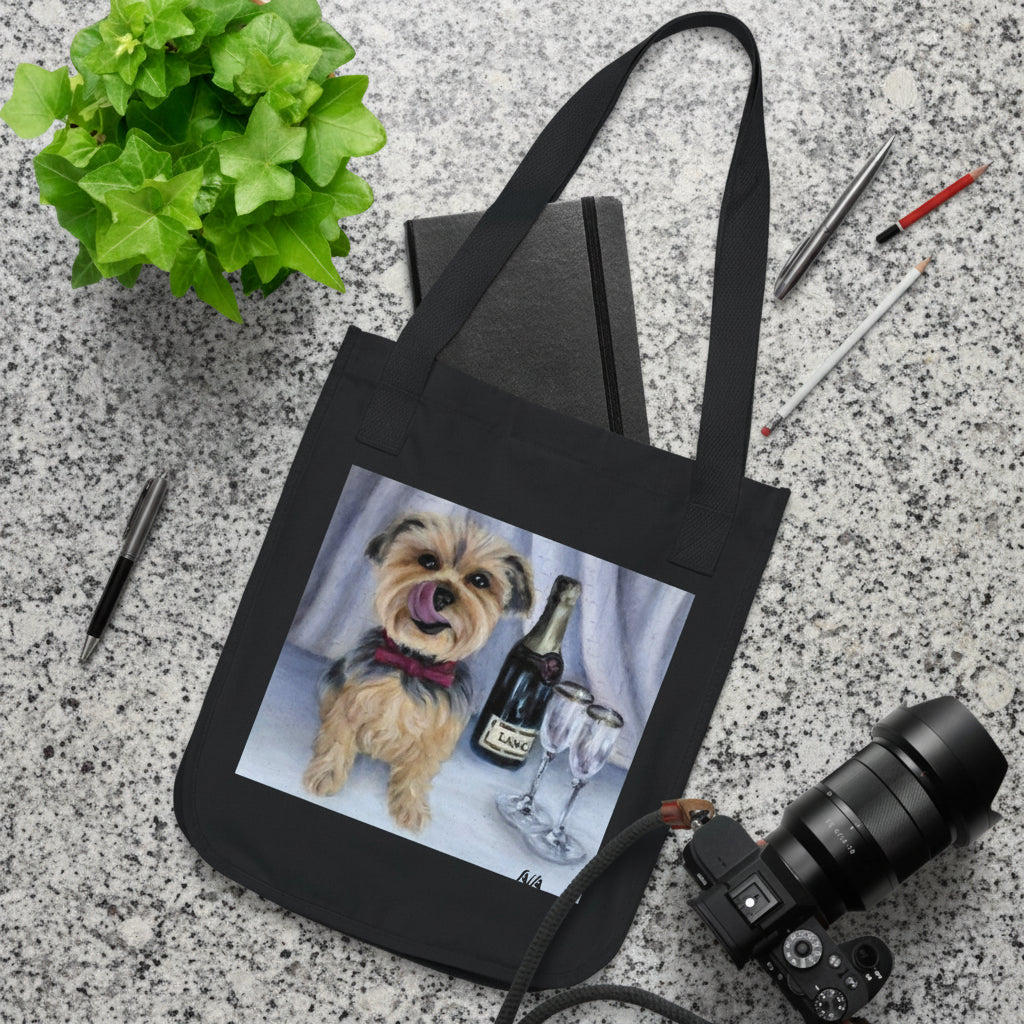 A black canvas tote bag with a custom printed illustration of a small dog next to wine glasses and a bottle