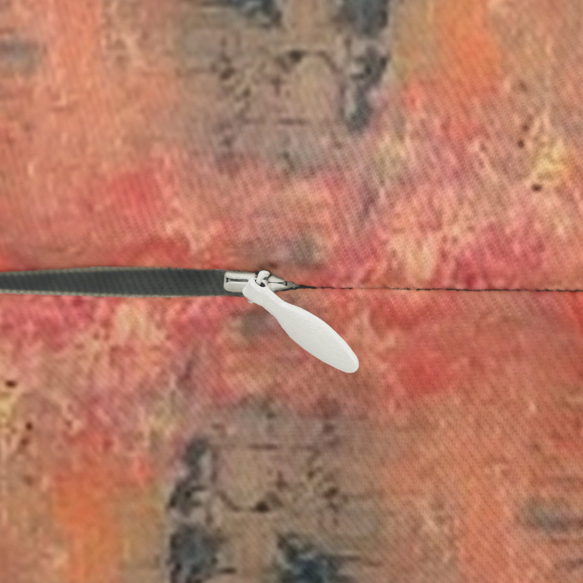 A close-up of a hidden zipper inset in  textured artist landscape print of red, orange, and brown tones.