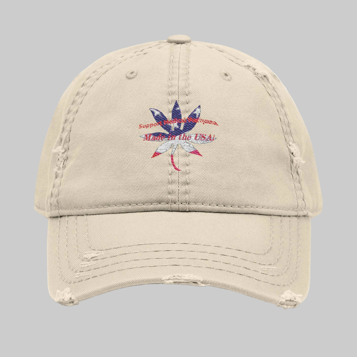 A distressed beige baseball cap with a small graphic on the front featuring a blue, white and red cannabis leaf with the text 'Support Medical Marijuana  Made in the USA!' will feed your vibe and get you noticed.