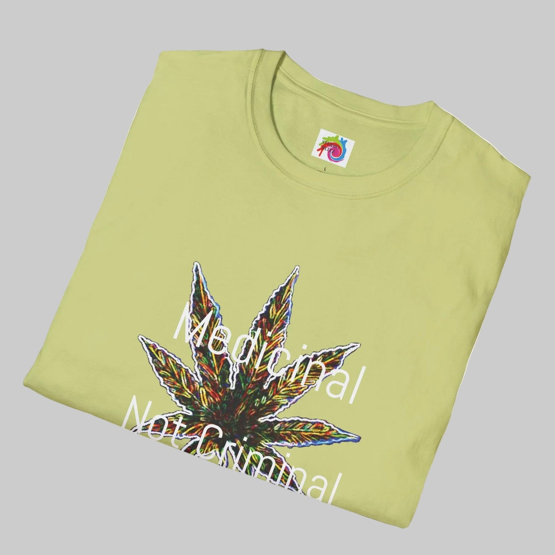 A folded pistachio t-shirt with a colorful cannabis leaf graphic and the text 'Medical Not Criminal' printed on the front