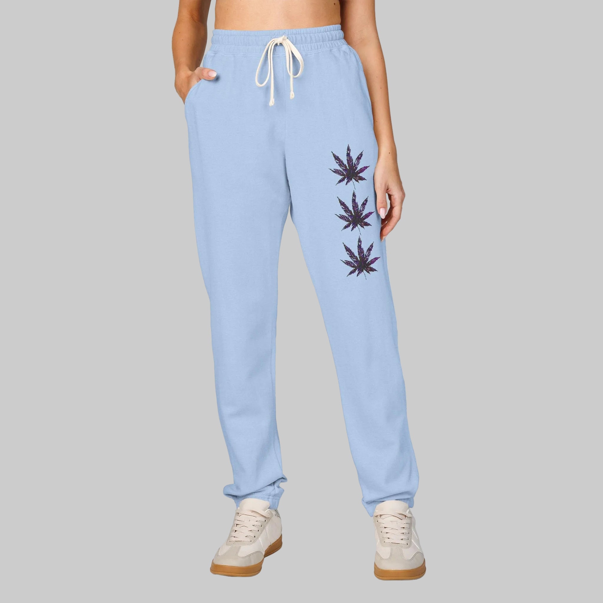 Hydrangea colored sweatpants with a white drawstring and three dark cannabis leaf graphics printed vertically on the left leg reveals your vibe