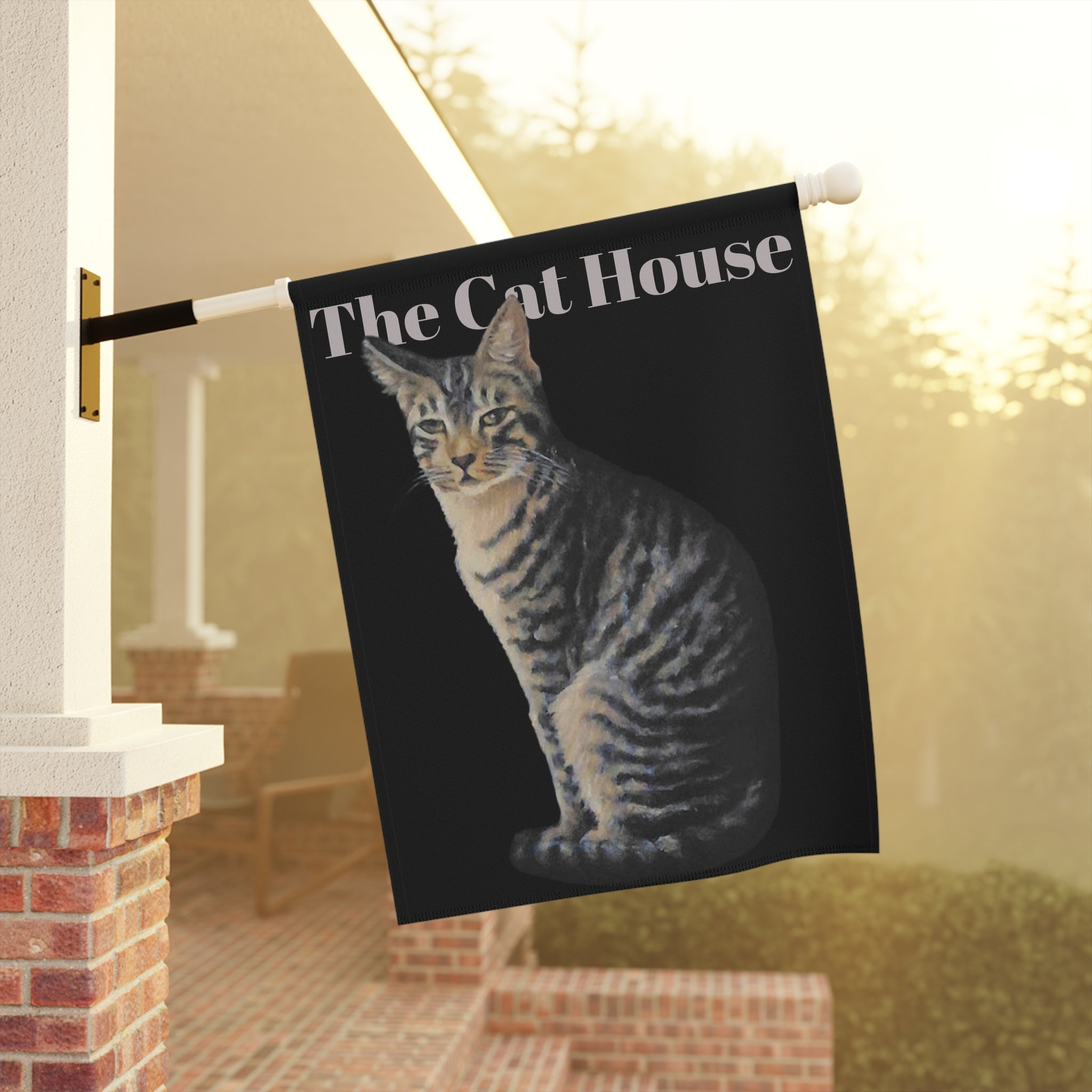 Flag with a cat design and 'The Cat House' text, hanging outdoors.