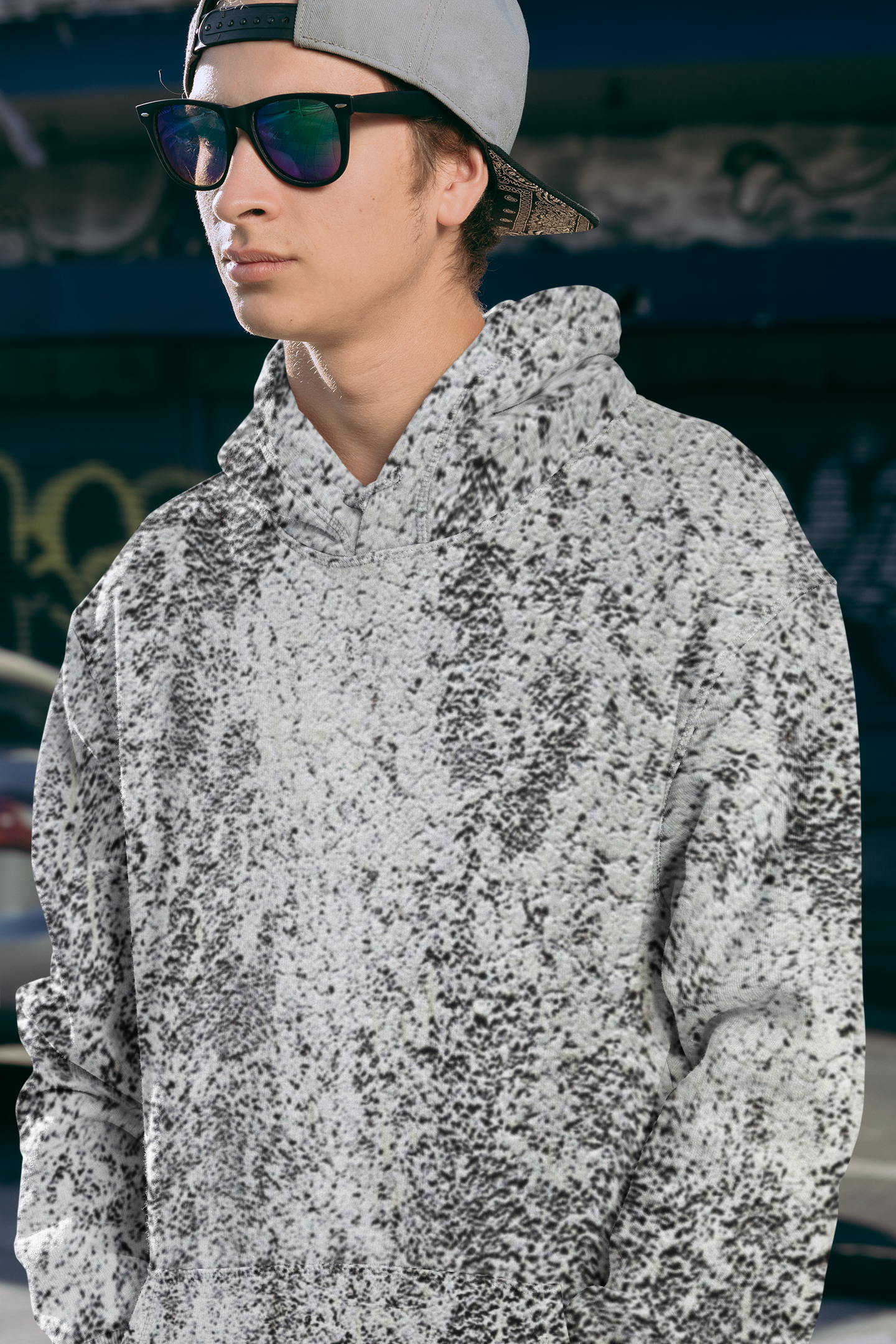 Person wearing a gray and white abstract hoodie with sunglasses and a cap.