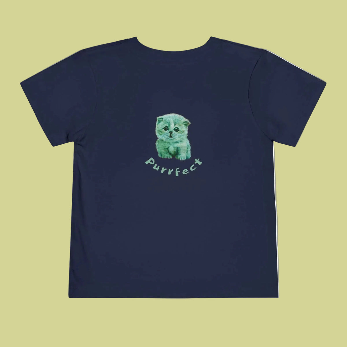 A toddlers navy blue short-sleeve t-shirt with a central graphic of a green and blue watercolor kitten sitting above the word 'purrfect' in a light green script font