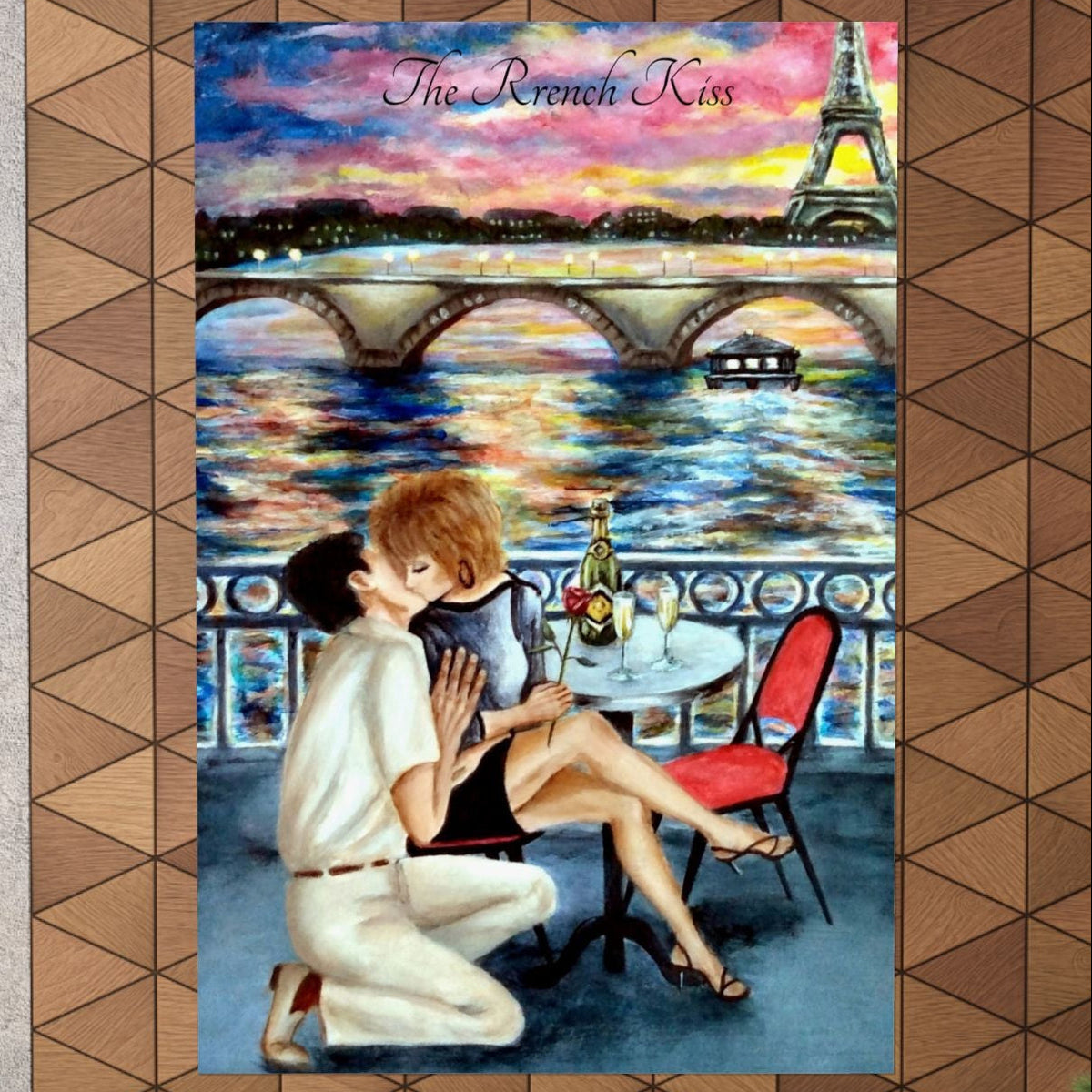 A framed-style wall art print depicting a romantic couple on a balcony overlooking a Parisian bridge and river, with the Eiffel Tower and colorful sky in the background. 
