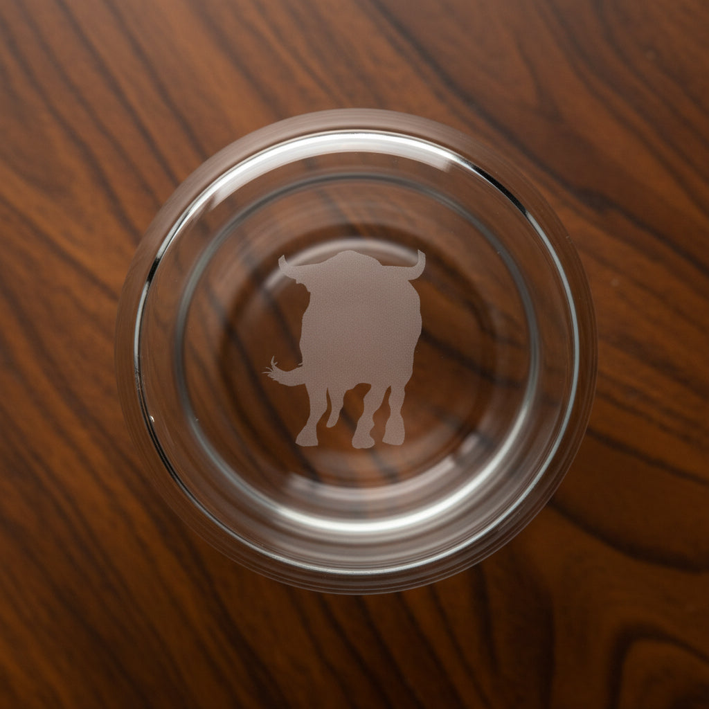 The heavy bottom of this whiskey glass is also etched with the charging bull