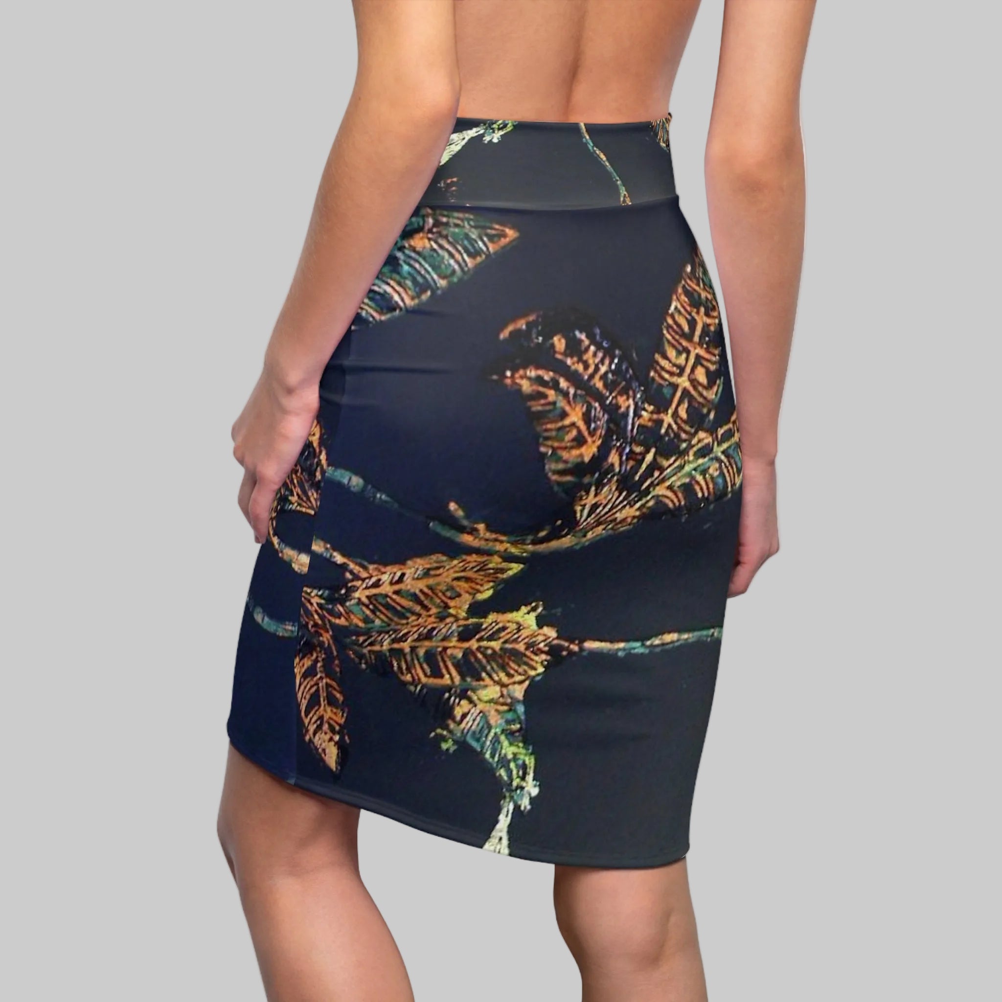 Fitted pencil skirt that stretches with you  in a dark base and a artistic leaf pattern in gold, green, and orange, shown from the back.