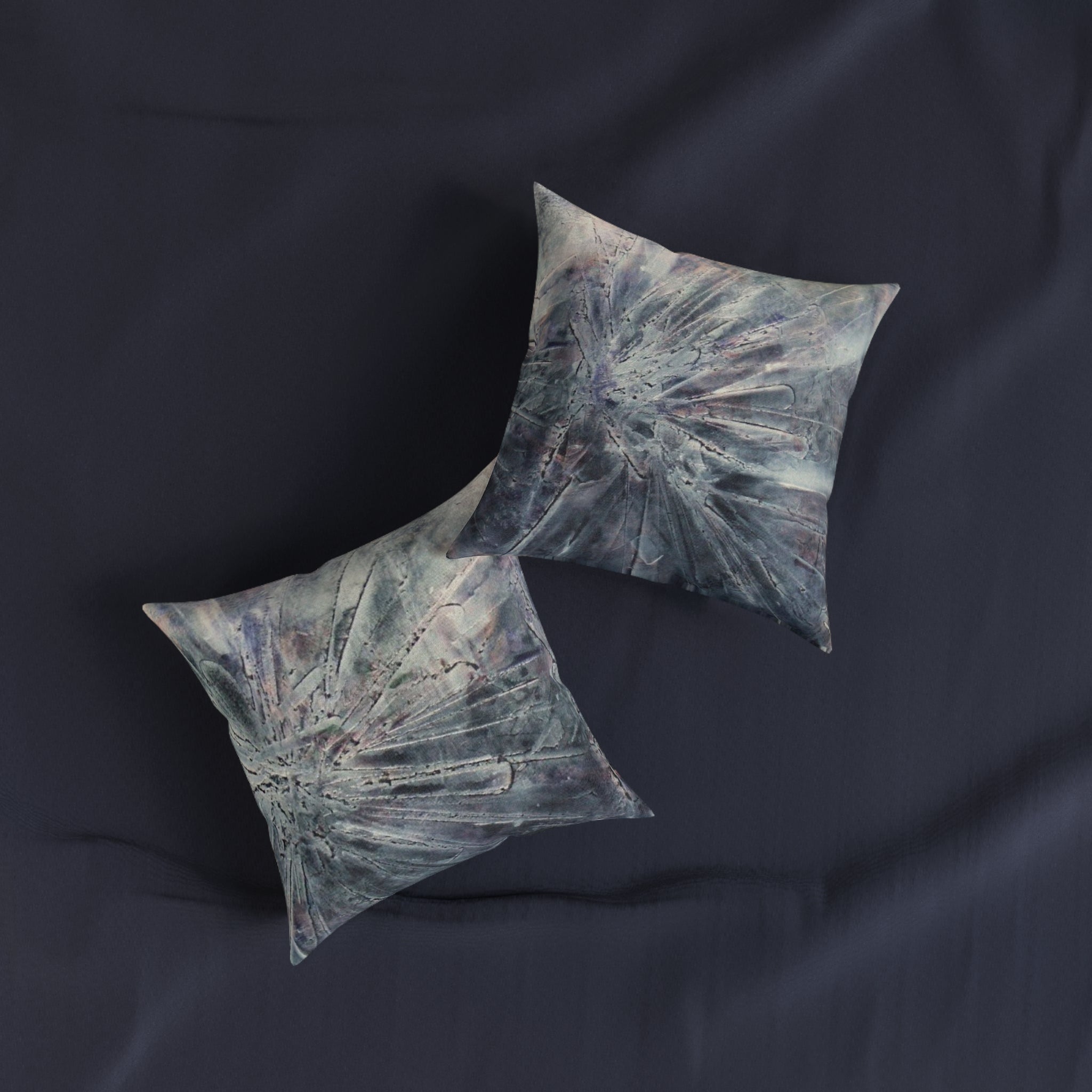 Two decorative pillows on a dark fabric background
