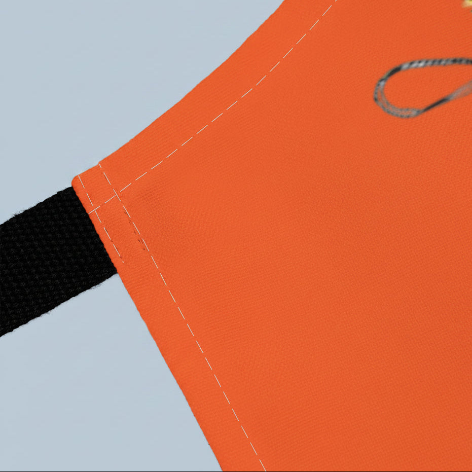 Close-up of an orange apron with a black strap and a small design 