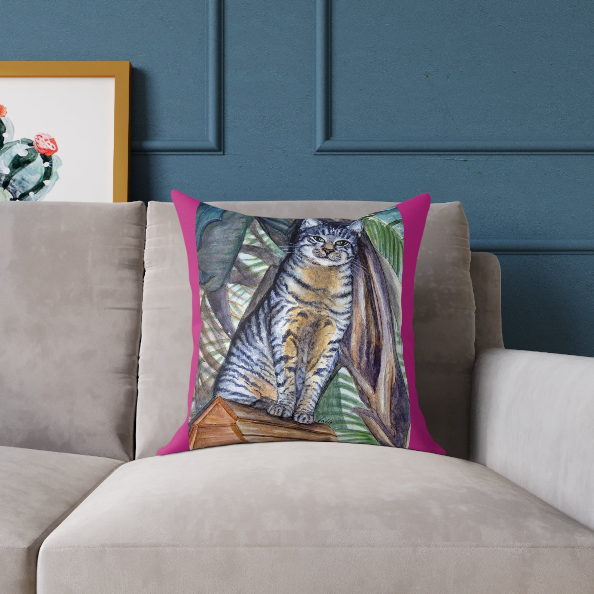 Decorative pillow with a cat design on a gray sofa against a blue wall.